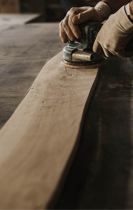 Unrecognizable manual worker using plane while working on a wood in a workshop 